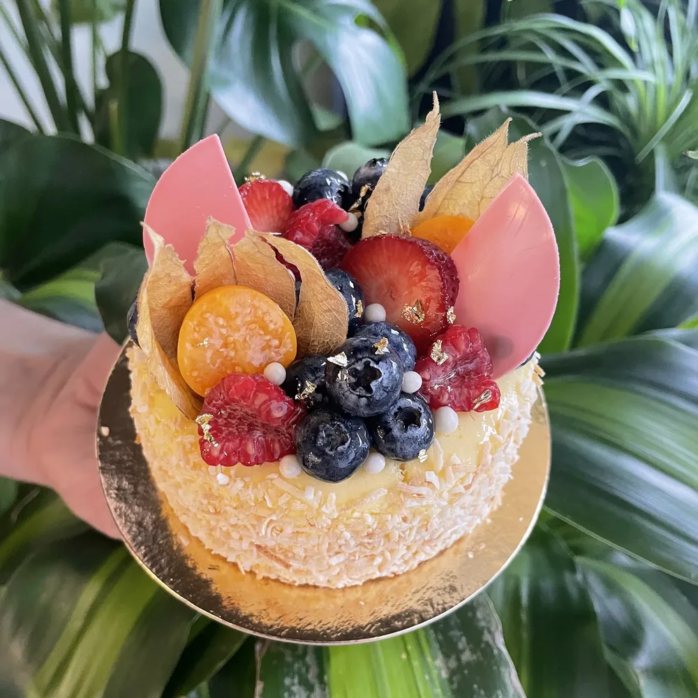 Passionfruit cheesecake topped with berries, physalis and pink chocolate