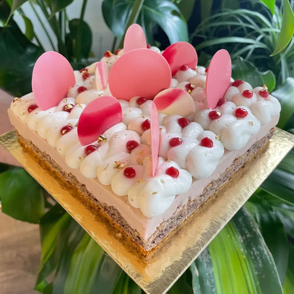 Strawberry-hazelnut torte with piped cream and pink chocolate petals